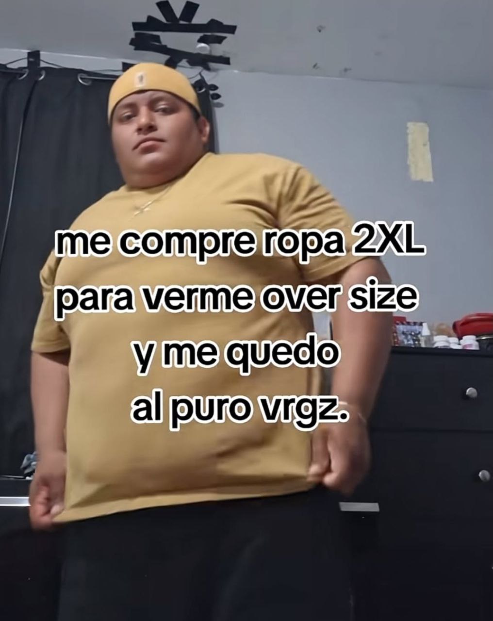 a man in a yellow shirt and black pants is standing in front of a black wall